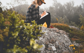 Woman writing in journal in nature