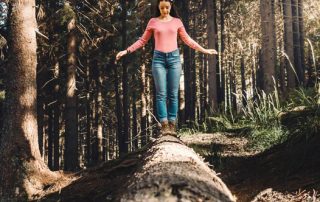 Woman walking on a fallen tree in the woods