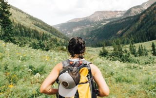 Back of woman wearing backpack hiking in the mountains