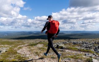 Man out trail running with large red backpack
